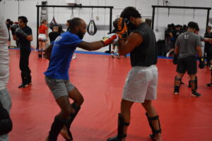 Mixed martial artists sparring in Gilbert gym, comparing MMA and BJJ strategies in training.