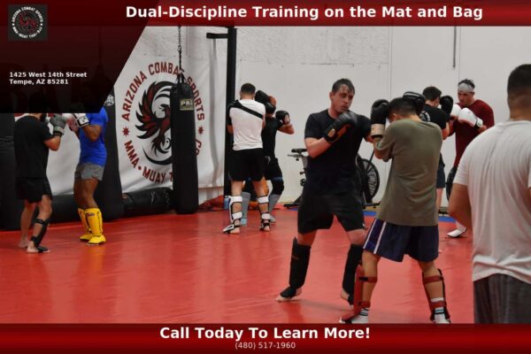 Adult student drilling BJJ guard pass with Muay Thai heavy bags in background at Arizona Combat Sports gym in Phoenix Arizona