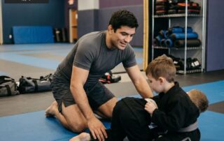 Two athletes drilling clinch work near an MMA cage at an East Valley gym in Arizona, with a Tempe skyline visible through large windows - Arizona Combat Sports